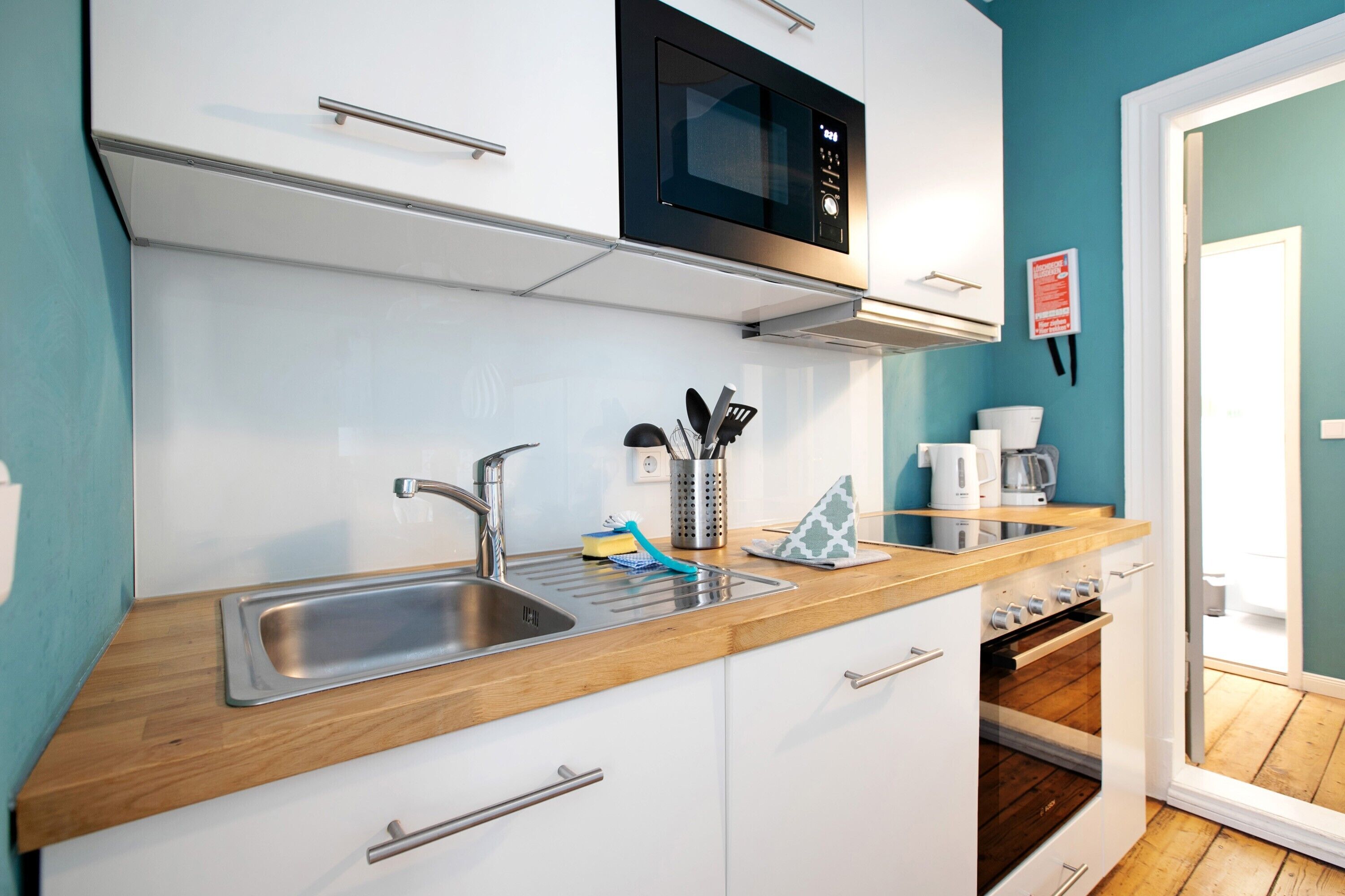 A modern kitchen with a stainless steel sink, a microwave, and a coffee maker.