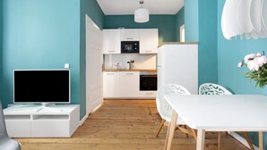 A modern kitchen with white cabinets, a microwave, and a dining area with a white table and chairs.