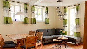 A room with a dining table, chairs, a sofa, a small round table with a vase, and a hanging light fixture. - Apartment 'Ferienwohnung Kammer' with Private Terrace, Shared Garden and Wi-Fi (Iphofen)