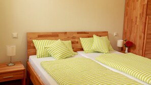Un lit double avec une literie à rayures, une tête de lit en bois, une table de chevet avec une lampe et une petite table de nuit avec une lampe.