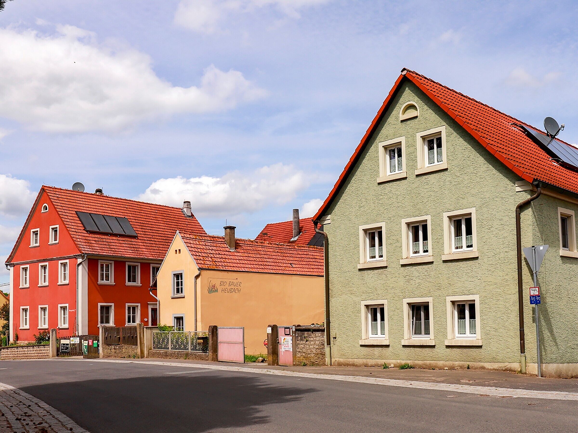 Una fila di edifici colorati con stili architettonici diversi, tra cui un edificio con pannelli solari e uno con un cartello visibile.