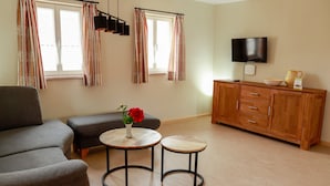 A living room with a sofa, two side tables, a wooden cabinet, a television, and striped curtains. - Apartment 'Ferienwohnung Stübla' with Private Terrace, Shared Garden and Wi-Fi (Iphofen)