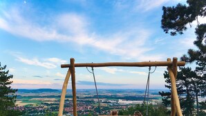 Un columpio de madera con un banco, con vistas a un paisaje pintoresco con campos y un pueblo distante.