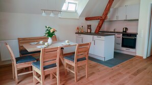 Una cocina acogedora con comedor, muebles de madera y vista a la cocina a través de una ventana.