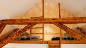 Un espacio tipo loft con techo alto, vigas de madera y un ventanal grande.
