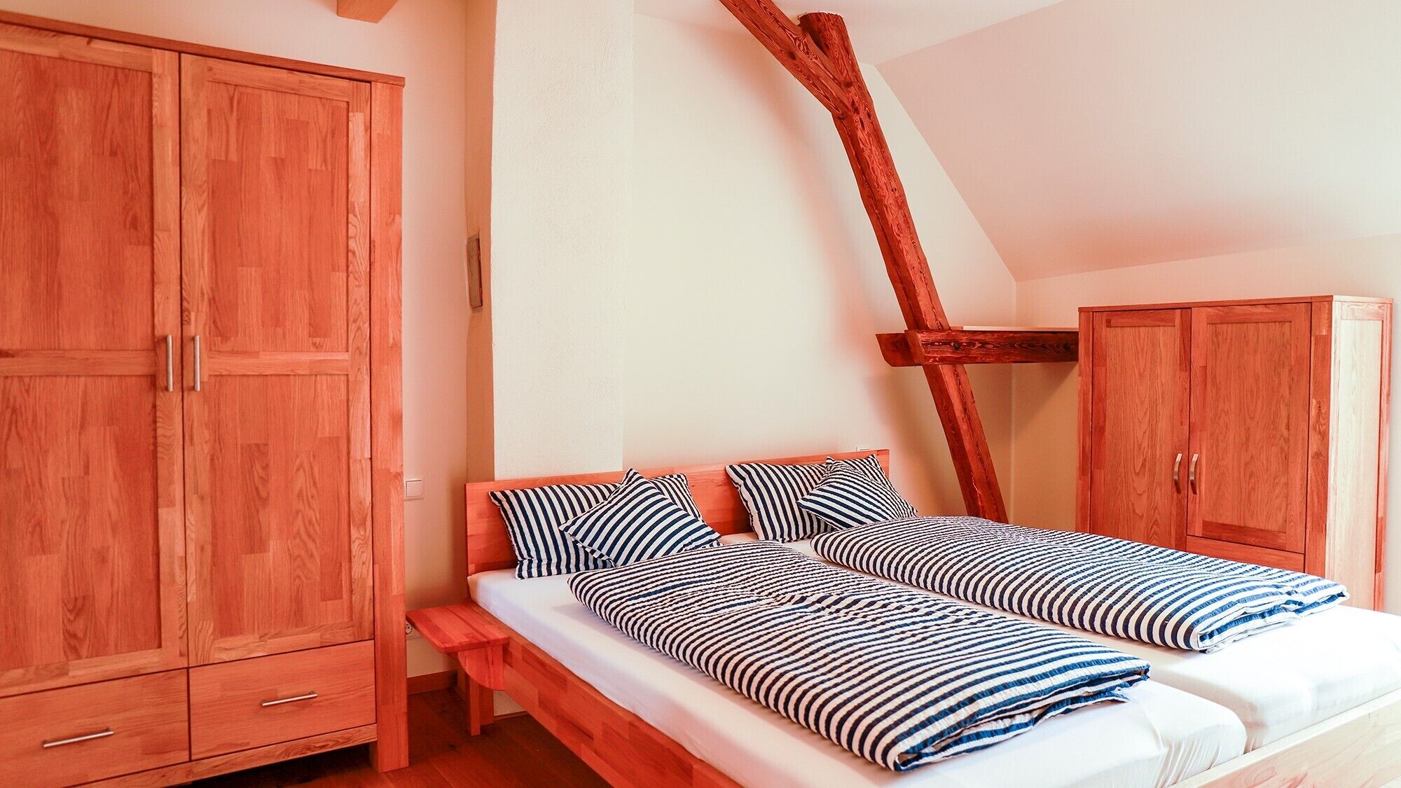 Un dormitorio con una cama, un armario y un banco de madera.