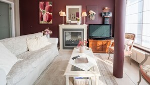 Ein Wohnzimmer mit Sofa, Couchtisch, Kamin, Fernseher und einem großen Fenster.