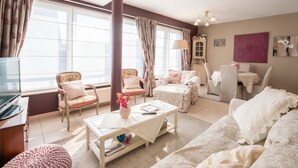 Ein gemütliches Wohnzimmer mit einer Couch, Sesseln, einem Couchtisch und einem Fernseher.