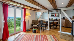Une pièce spacieuse dotée d’une grande porte-fenêtre coulissante, d’un plafond en bois, d’un coin repas et d’une cuisine.