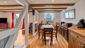 Un coin repas avec une table et des chaises en bois, un comptoir de cuisine équipé d’appareils électroménagers et un téléviseur.