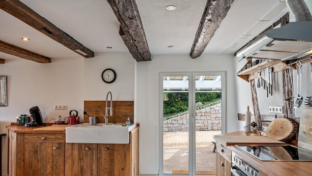Une cuisine avec des meubles de rangement en bois, un évier, une cuisinière et une grande fenêtre.