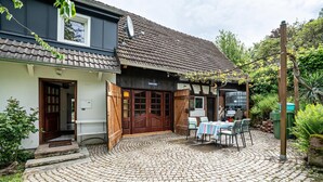 Un bâtiment doté d’une cour pavée, d’une porte en bois et d’une table entourée de chaises.
