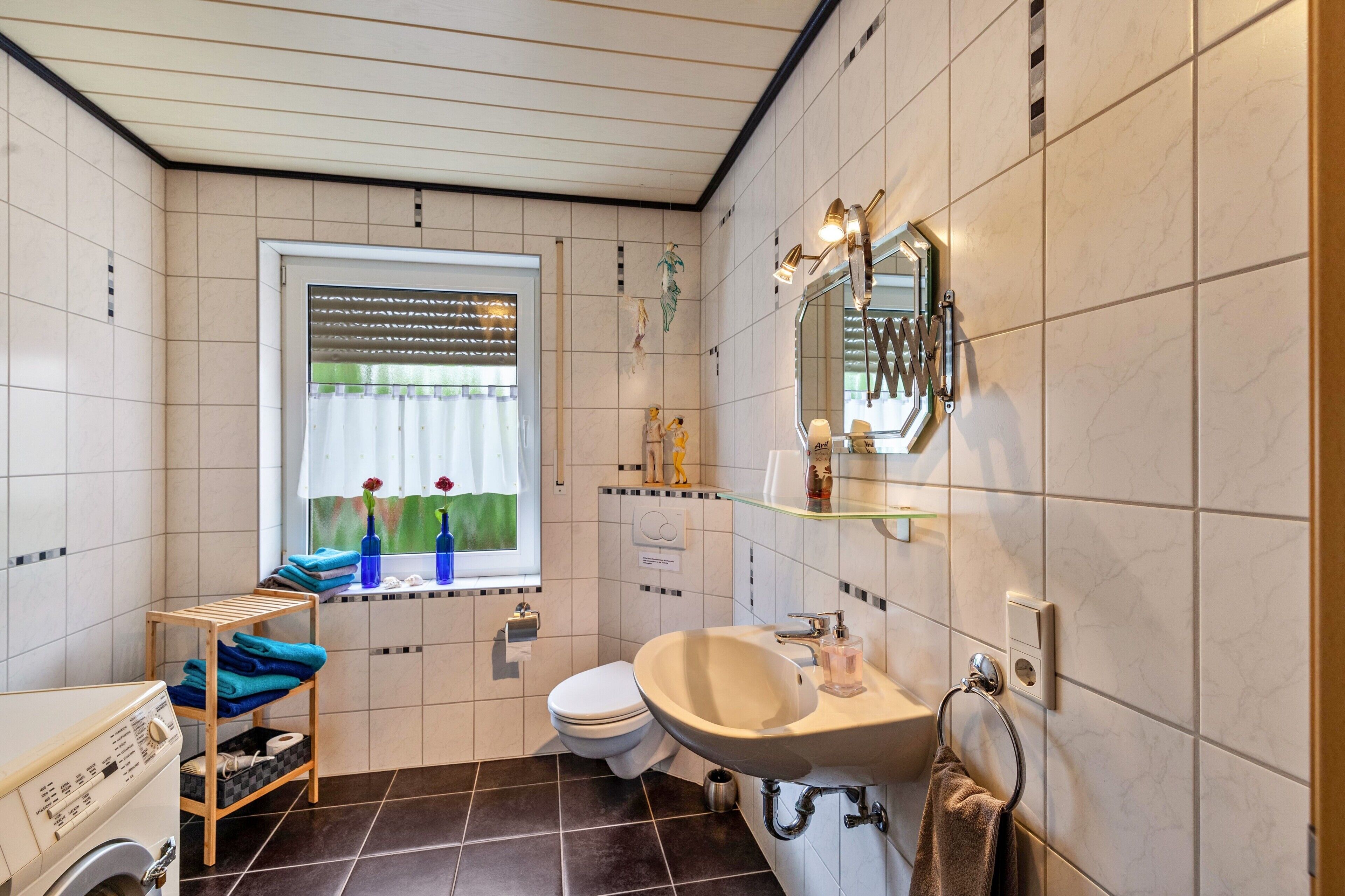Baño con inodoro, lavabo, espejo y ventana con cortinas.