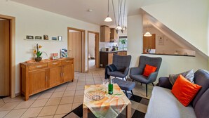 A modern living room with a sofa, armchairs, a wooden cabinet, and a dining area with a kitchen in the background. - Apartment 'Tulpe' with Balcony and Wi-Fi (Kalkar-Wissel)