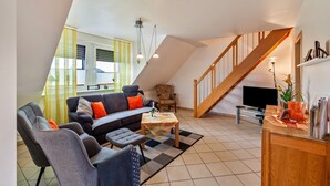 A living room with a sofa, chairs, a coffee table, a TV, and a staircase. - Apartment 'Tulpe' with Balcony and Wi-Fi (Kalkar-Wissel)