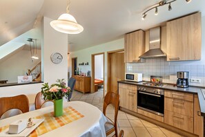 Eine moderne Küche mit Holzausstattung, einem Backofen und einer Mikrowelle.