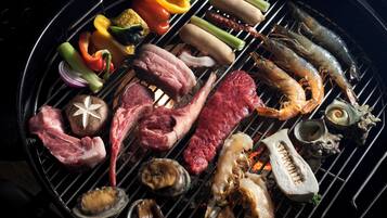 Diversos tipos de carne e frutos do mar grelhando na churrasqueira.