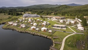 A yurt-style accommodation with a lake view, surrounded by lush greenery and mountains. - STARVILLE (Seogwipo)