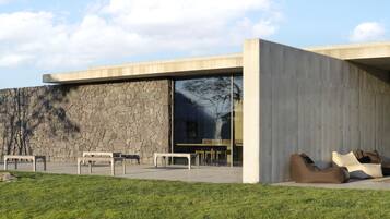 A modern building with a stone facade, large glass windows, and outdoor seating.