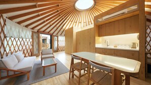 A modern interior with a central dining table, wooden furniture, and a kitchen area with a sink and countertop. - STARVILLE (Seogwipo)