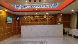 A hotel reception area with a marble counter, clocks, and a TV screen. - Hotel living international ltd (Dhaka)