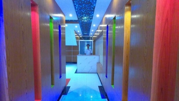 A modern hallway with a central reception desk, illuminated by overhead lights and a patterned ceiling. - Hotel living international ltd (Dhaka)