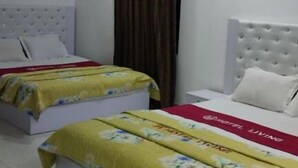 A hotel room with two beds, a ceiling fan, an air conditioning unit, and a curtain. - Hotel living international ltd (Dhaka)