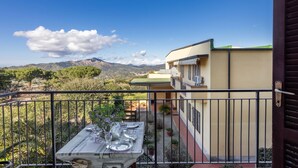 Un balcón con mesa lista para comer, con vistas a un paisaje montañoso.