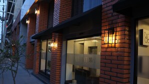 Hotellin julkisivu on tehty tiilestä, siinä on suuret lasi-ikkunat ja ikkunoista näkyy ulkona oleva oleskelualue.