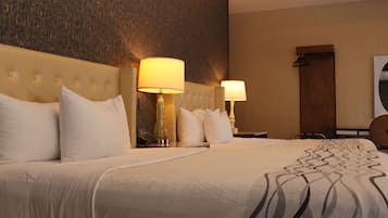 A hotel room with a large bed, two bedside lamps, a wooden headboard, and a wall-mounted coat rack.