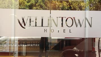A hotel sign with the name "WELLINGTON HOTEL" and a reflection of a vehicle and interior.