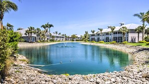A resort with a central pond, palm trees, and modern buildings with balconies. - Naples Resort Condo on 2 Championship Golf Courses (Naples)