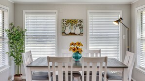 Ein Essbereich mit Tisch, Stühlen, einer Vase mit Sonnenblumen und einem Gemälde an der Wand.