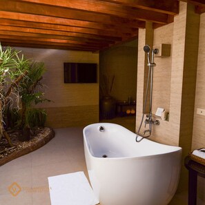 Un baño moderno con una bañera independiente, ducha y una pequeña mesa con una cesta.
