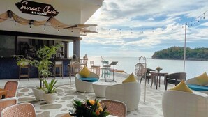 A bar lounge with outdoor seating, a view of the sea, and a sign reading "Sunset Cove Bar Lounge". - Villa Angelina Luxury Suites (Dapitan)