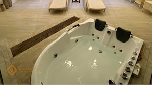 A luxurious suite with a large jacuzzi, a dining area, and a view of the adjacent room. - Villa Angelina Luxury Suites (Dapitan)