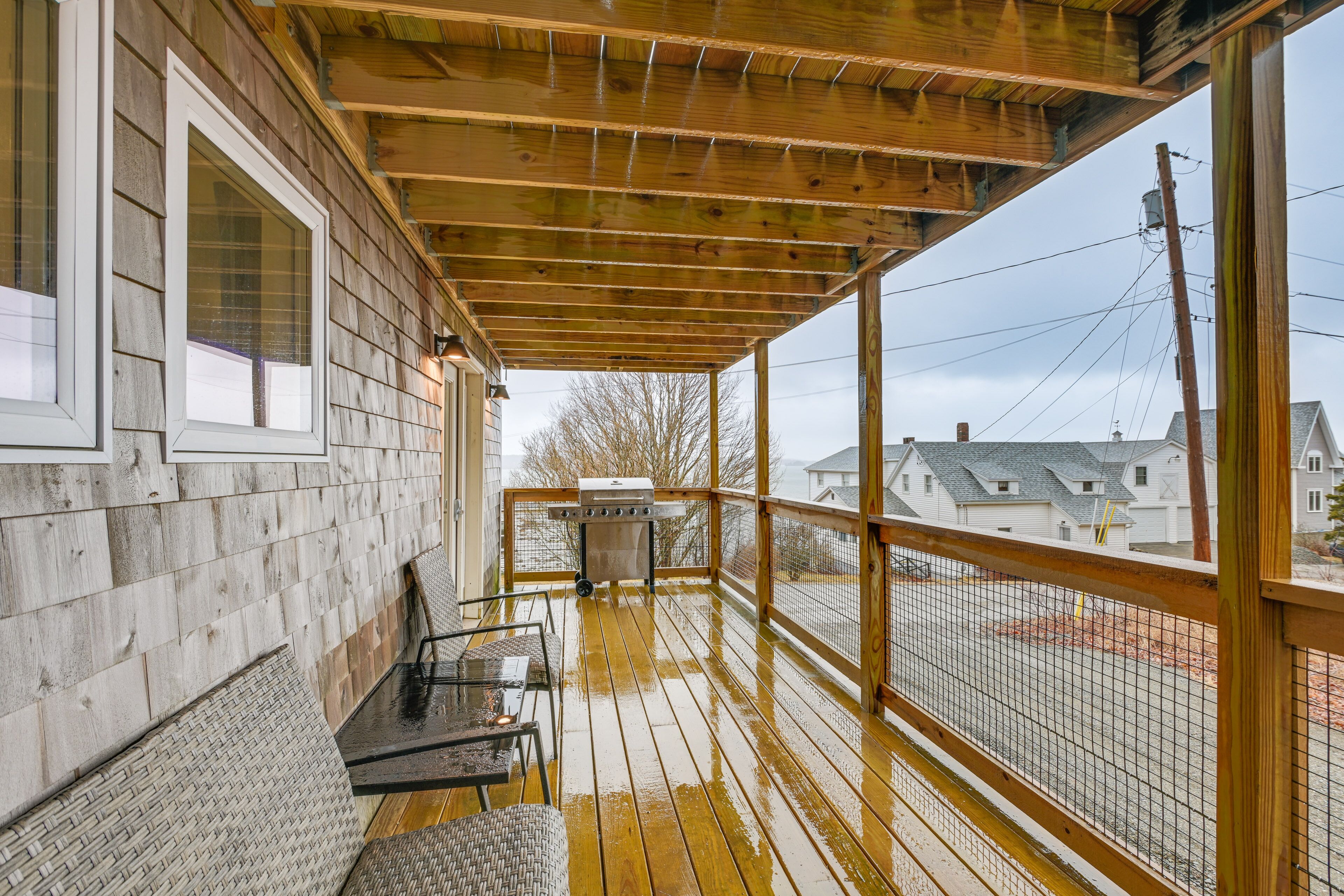 A covered porch with a grill, seating, and a view of the neighborhood.