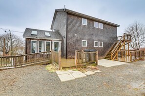 Et toetagers hus med en træterrasse, en trappe og en overdækket veranda.