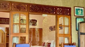 A traditional room with wooden furniture, a tiled floor, and a ceiling fan. - Narafa's Guest House (Karangasem)