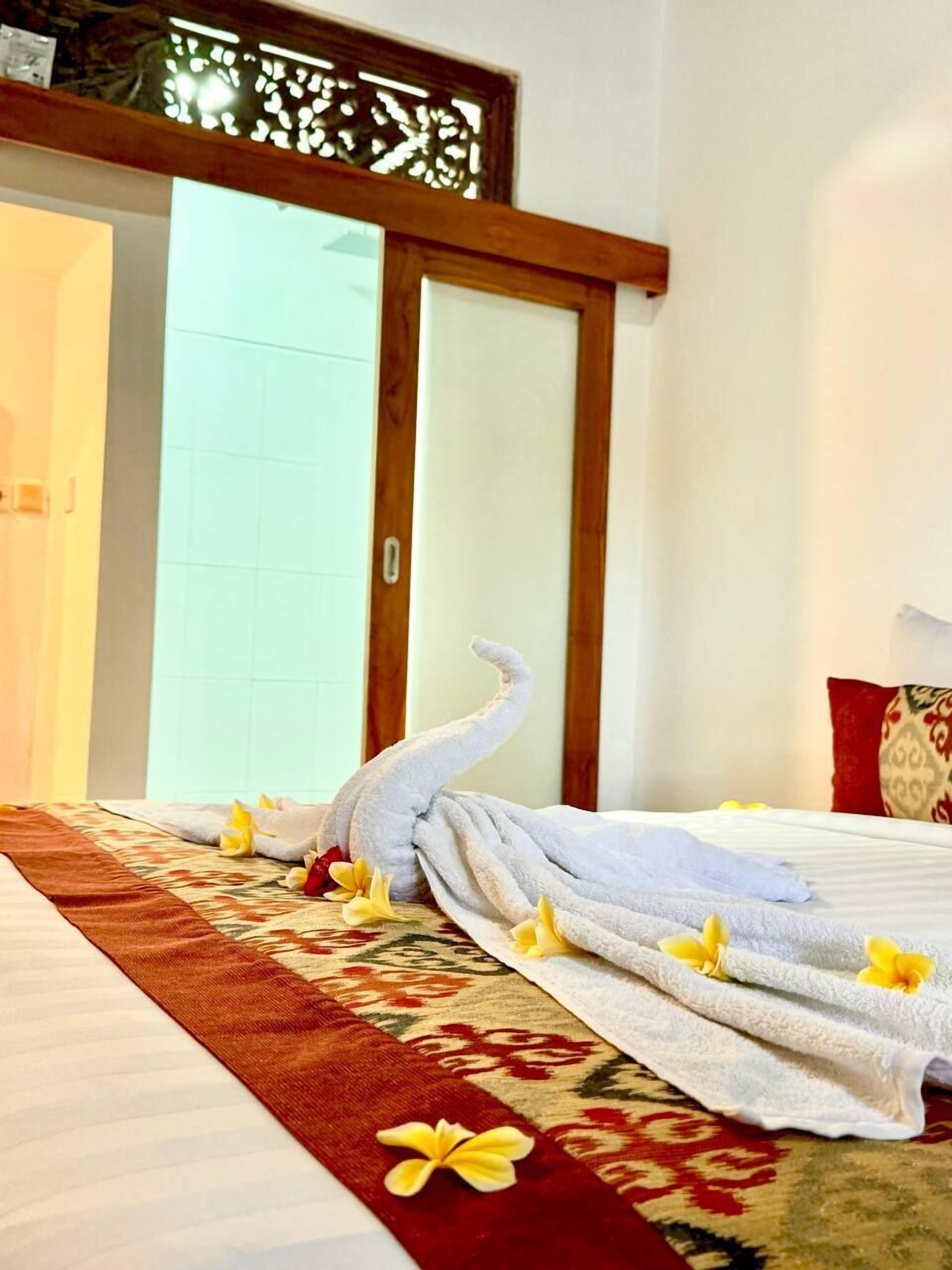 A hotel room with a bed, a wooden door, and a patterned rug.