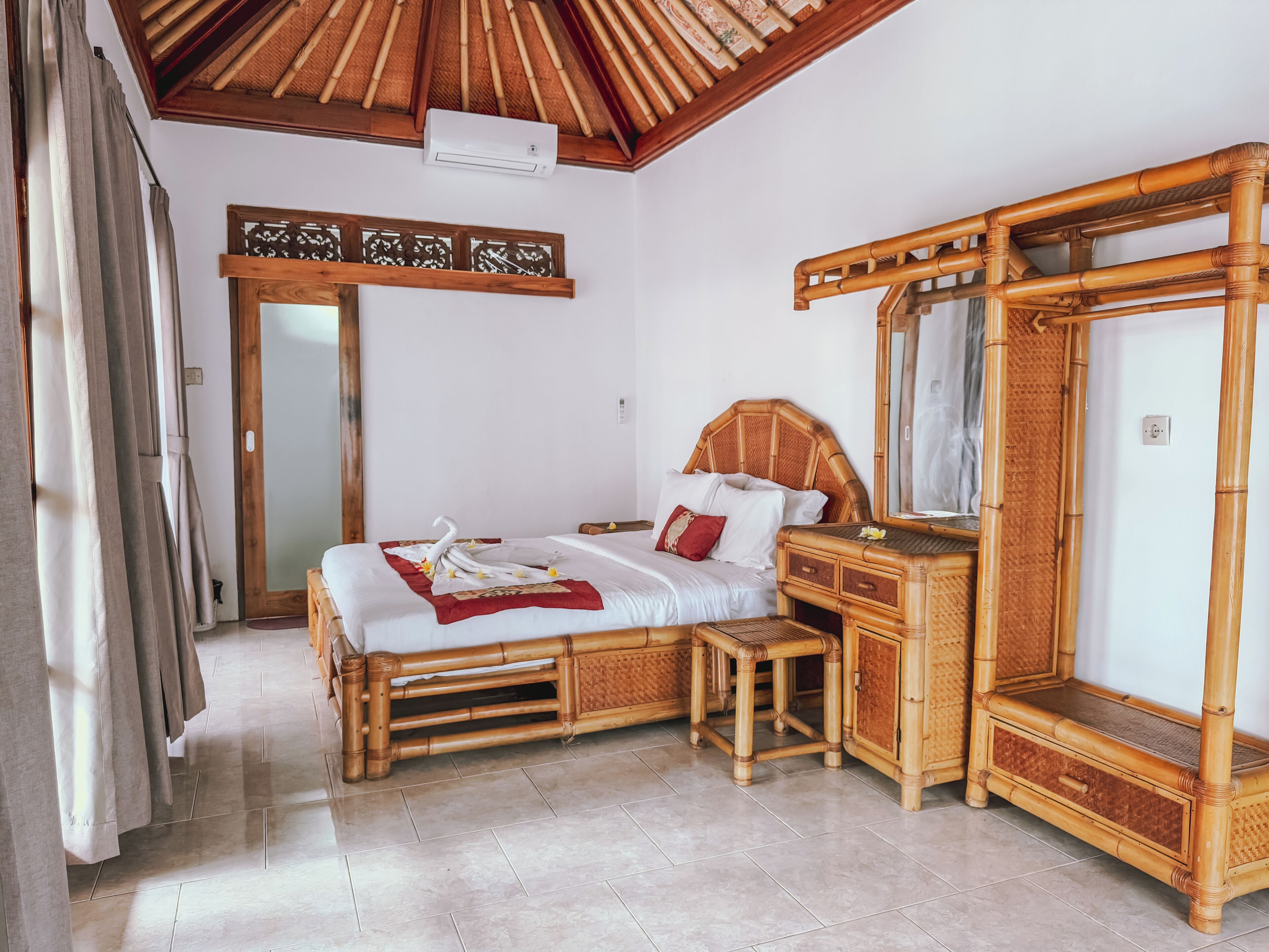 A room with a bed, a wooden dresser, a mirror, and a ceiling fan.
