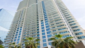 A high-rise building with multiple balconies and a glass facade. - Luxurious 1BR Oasis Panoramic Views (Dubai)