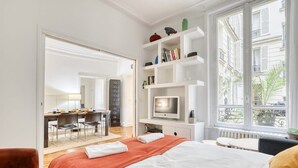 Una habitación de hotel moderna con cama, escritorio, televisor y estantería.