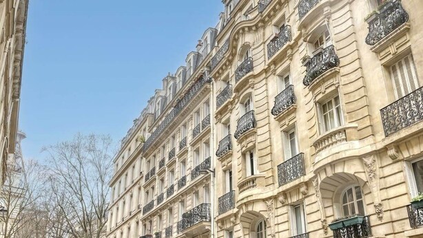 Un edificio de varios pisos con balcones ornamentados y detalles arquitectónicos clásicos.