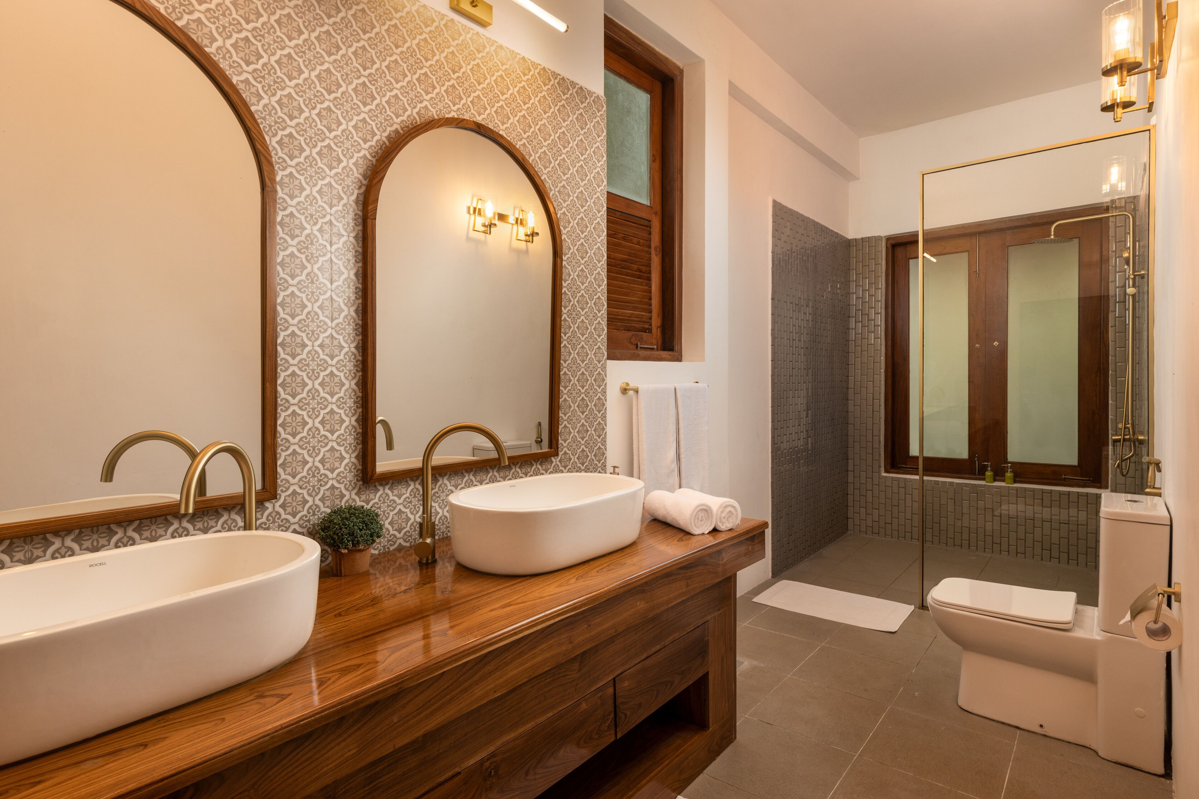 A modern bathroom with two sinks, a large mirror, and a shower area.