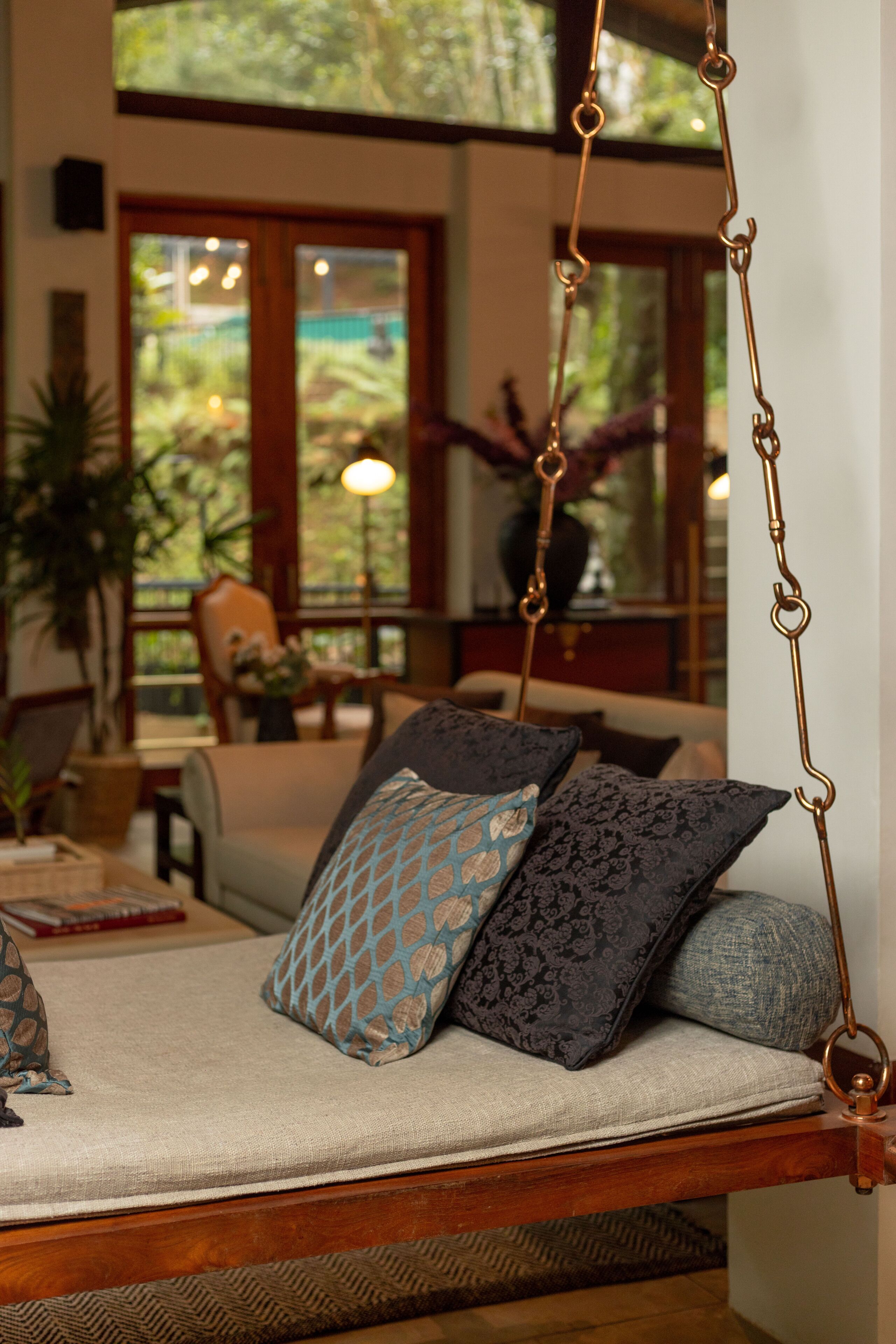 A hanging chair with a cushioned seat and backrest, suspended by a metal chain.