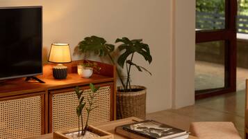 A living room with a television, books, a lamp, and a large painting on the wall.