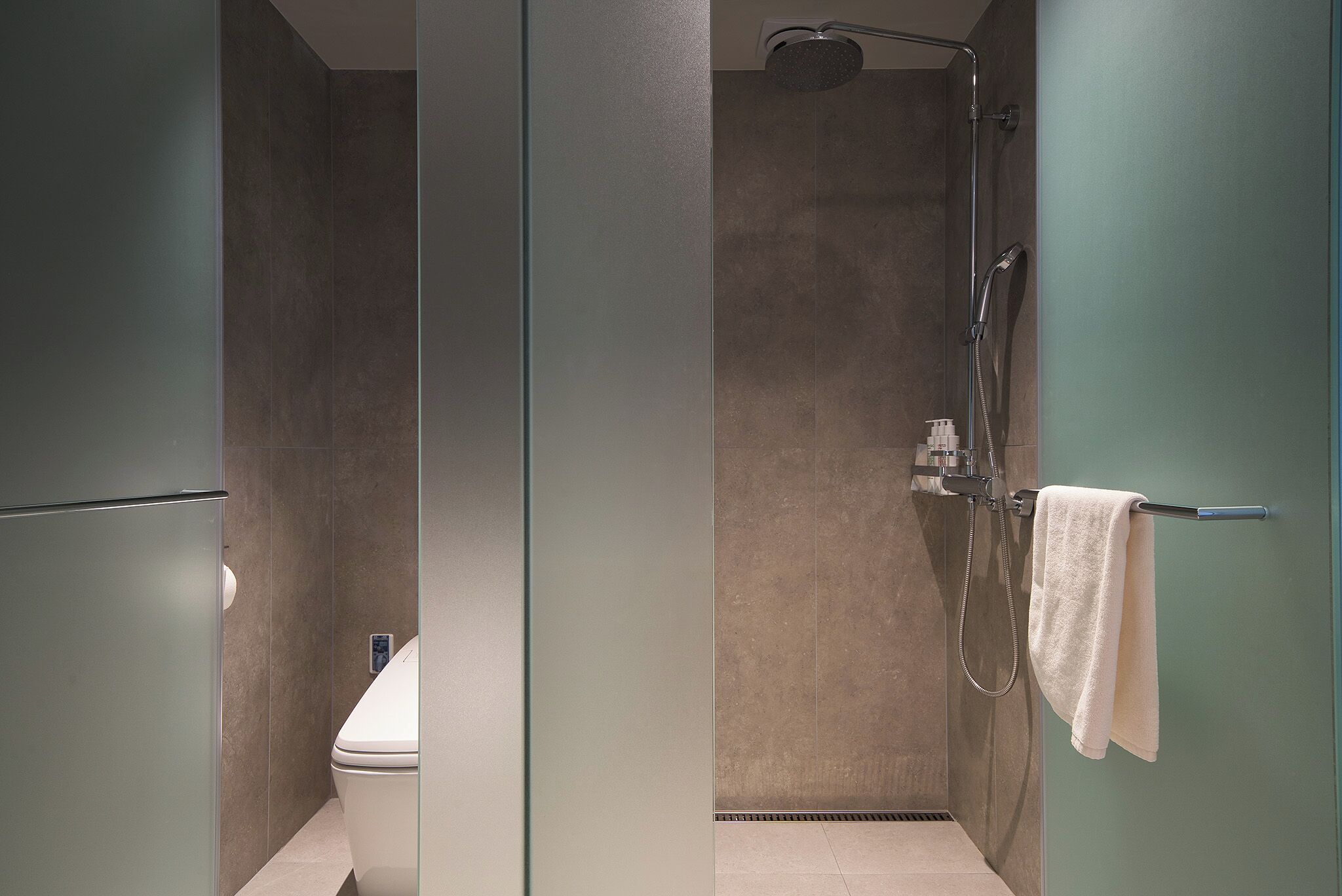 A modern bathroom with a glass partition, a shower, and a toilet.