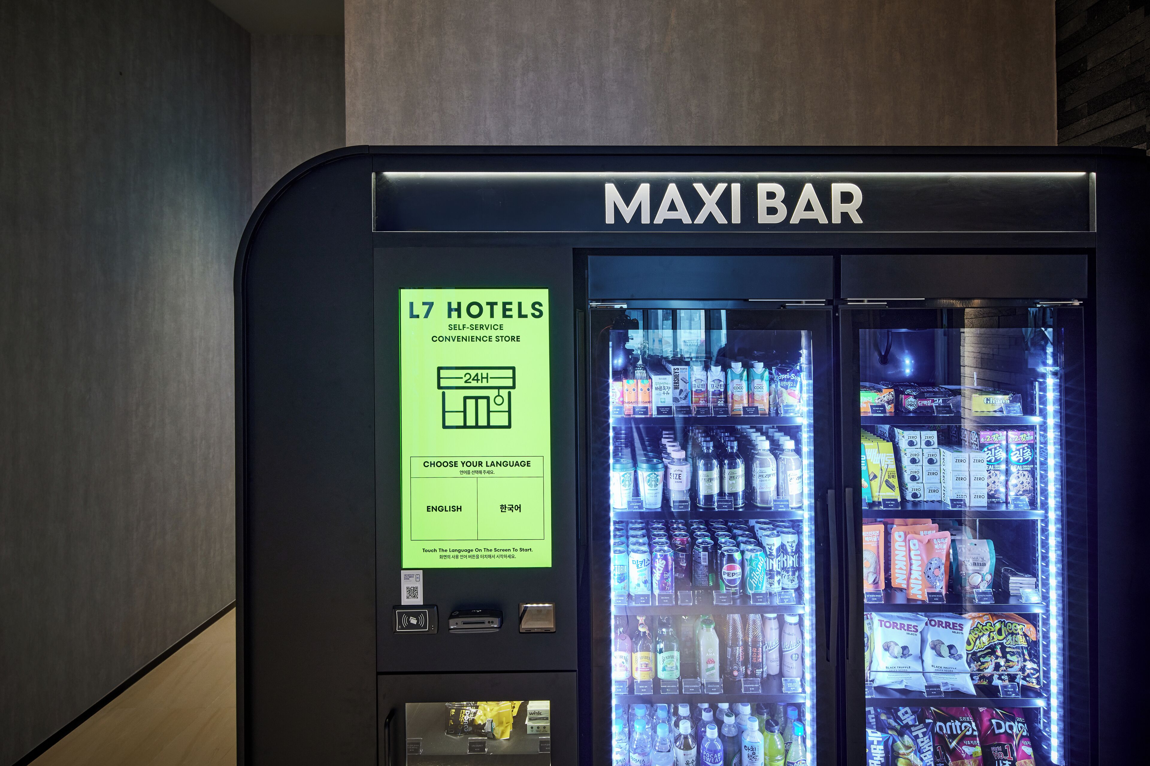 A self-service convenience store with a digital display for language selection and a variety of beverages and snacks.