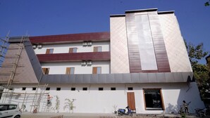 A multi-story building with a modern design, featuring a large entrance with a sign that reads "PUSHPDEEP RESIDENCY."